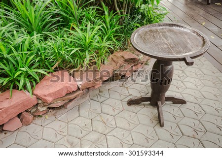 Small teak wooden circle table in green garden