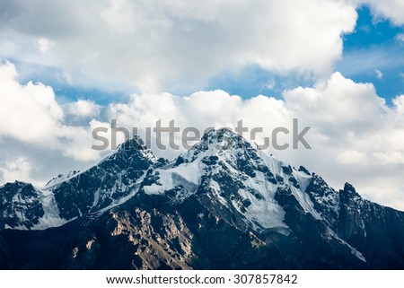 Top of snowy rock mountain on cloudy background