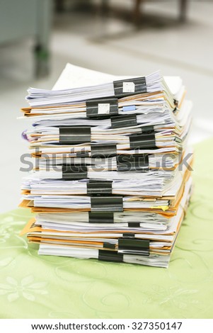 Big stack of business report paper files with black clips