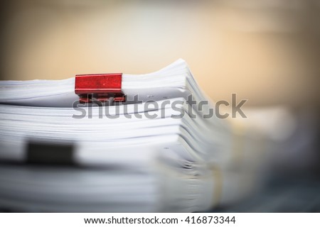 Stack of business report paper files with red and black clips