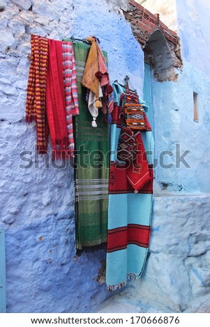Moroccan blankets and clothing hanging on a blue wall