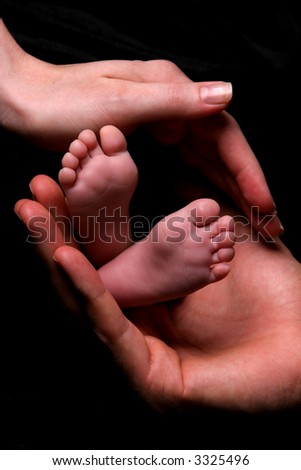 mom dad holding newborn\'s feet