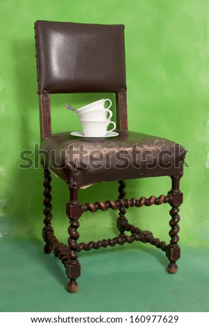 White cups with a saucer on a vintage chair