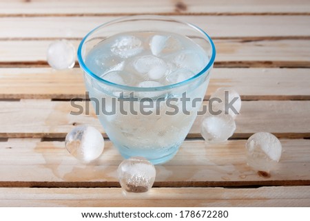 glass full of pure water with ice balls on a wood
