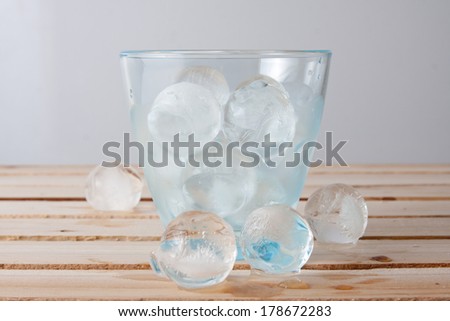 Water glass full of ice balls on a wood