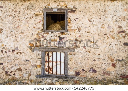Mouth or old wooden window in barn with alpacas dry grass and straw inside. Old stone Wall revoked