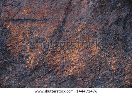 Texture or background of rough stone with cracks and veins of ocher, brown, gray, black and oxides