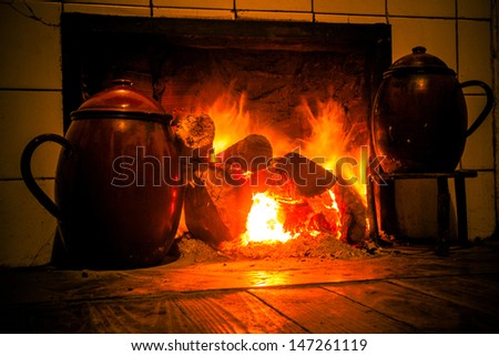 Chimney, kitchen hearth of burning rural house. Ancient scene cooking with two stews in trivet to the fire. Fireplace, stove on at home farmhouse. Scene two ancient cooking pots on trivets fire