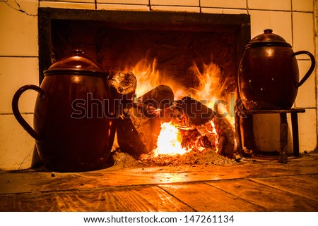 Chimney, kitchen hearth of burning rural house. Fireplace, stove on at home farmhouse. Fireplace, home farmhouse kitchen on. Tint old scene. Cooking pots on trivets two fire