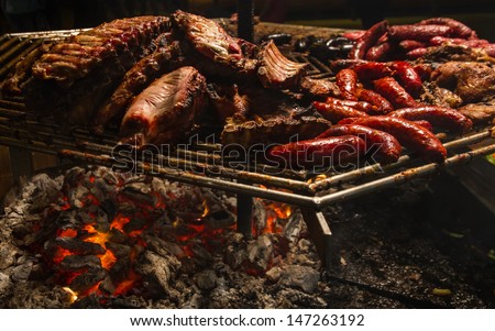 mixed grill roast beef grilled  with smoke of burning roast meat and in fair outdoors. Ribs and pork, beef, veal, lamb, sausages and black pudding