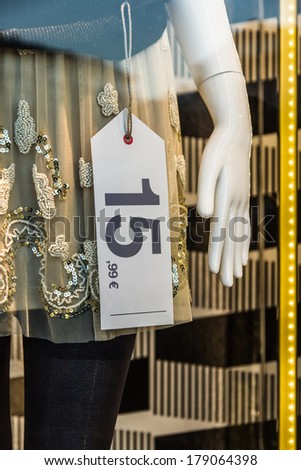 Price tag hanging in storefront mannequin in fashion shop -