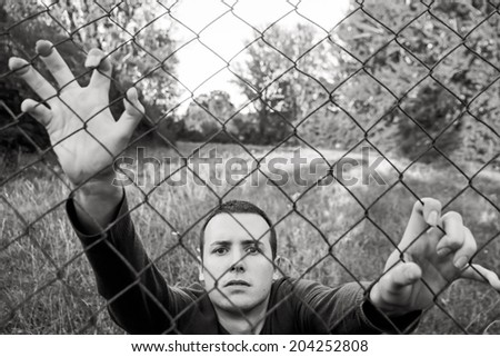 Young man looking at camera after prisoners wire or wire mesh in nature