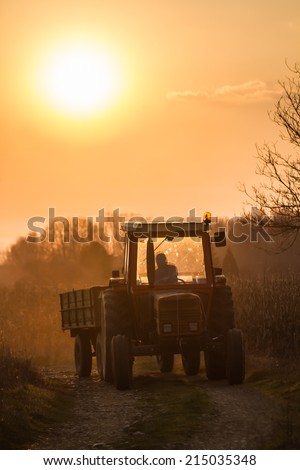 Tractor-trailer approaching from a dirt road to sunset