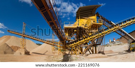 Machinery and classification according gravel size distribution via conveyor belts and piles of sand and records in mountain landscape