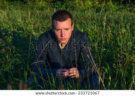 Young Man Sitting on the Grass - Young  man pensive sitting on the spring grass and sunset light