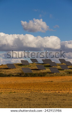 Plates or solar panels to the sun in the field with clear sky and fluffy clouds