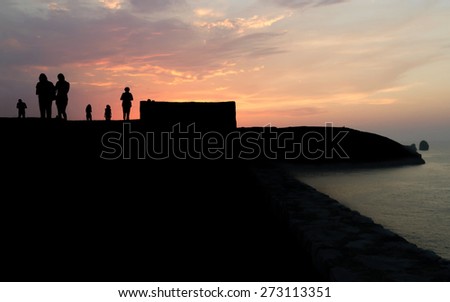 Silhouettes of people silhouetted against a sky enjoying a beautiful sunset, a walk along the sea coast of Llanes Asturias