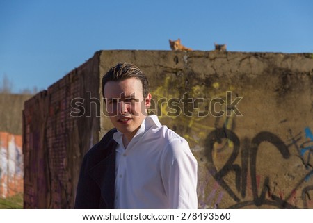 Stylish Young Man - Smart young, outdoors, white shirt and jacket hanging man, bottom painted brick wall with graffiti and cats at the top