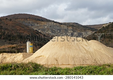 Pierced mountain quarry for stone quarrying and sand. Sand Mountain gravel pit in the foreground in silos and electrical turret