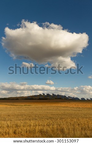 Plates or solar panels to the sun in the field with clear sky and above big cloud hiding the sun