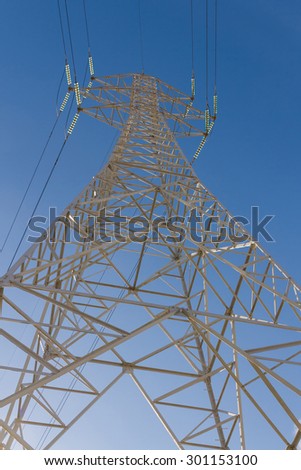 Electricity distribution tower seen from below on blue sky background