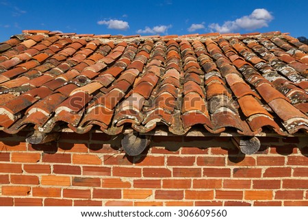 Roof with old tiles on a stand to save the farm tools, built with bricks and sky background