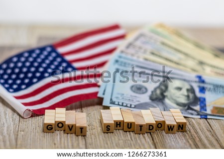 Government Shutdown USA concept with American flag and money bills on white background and wooden board