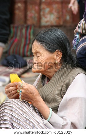 LHASA, TIBET - SEPTEMBER 25: unidentified pilgrim woman reads prayer flag to show her piety to Buddha and meditate on the threshold of the Jokhang Temple on September 25, 2009 in Lhasa, Tibet, China