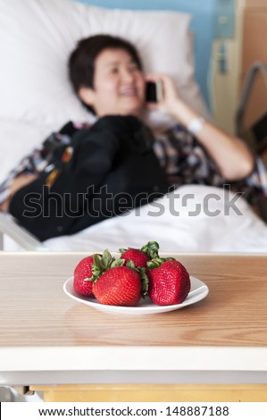Strawberry for Asian woman talking on the phone and recovering from shoulder operation in hospital