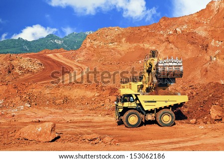 Excavator loading lignite stones in open pit mine - northern Thailand