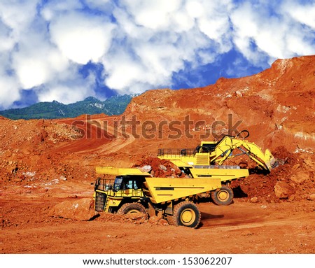 Excavator loading lignite stone in open pit mine - northern Thailand