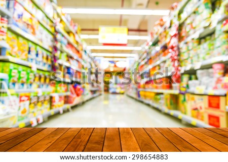 wood plank over blurred image of supermarket people shopping - product shelf - business concept