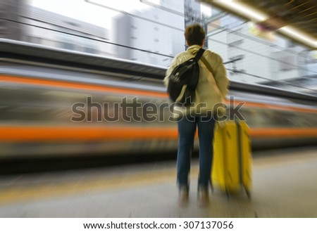 unrecognized young woman waiting for train on platform station - blurred image motion blur