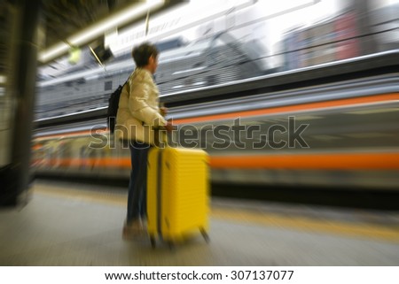 unrecognized young woman waiting for train on platform station - blurred image motion blur