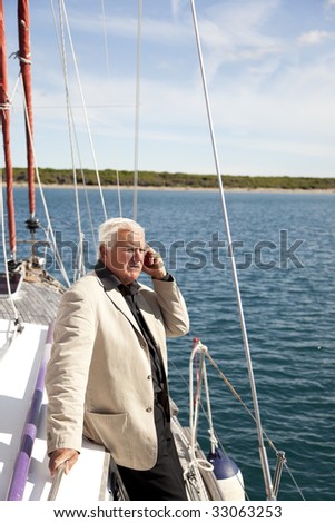 The businessman worries about his business while on the vacation on the sailboat.