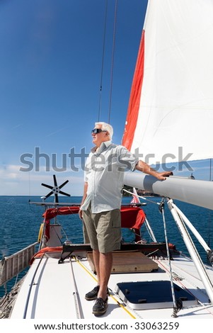 The senior man enjoy his vacation on the sailboat.