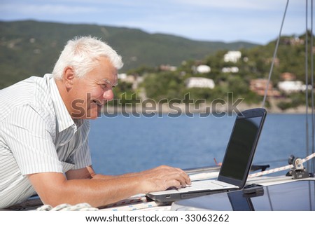 The senior man using the laptop on the sailboat.
