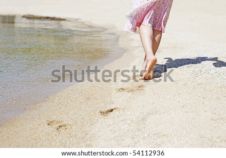 The woman walking on the sandy beach with bear feet.
