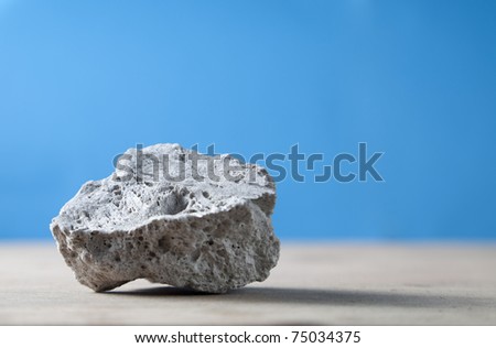 Raw pumice stone on wooden surface, light weight and with rough surface.