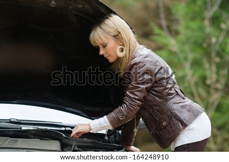 Young woman at broken car in the forest
