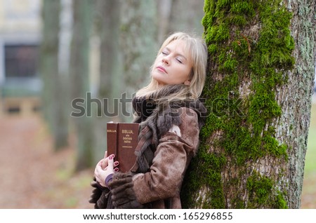 Young woman with a Bible in the alley of park