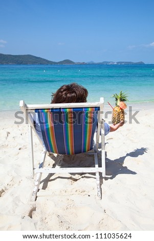 Woman relaxing with cocktail on the chair near the sea