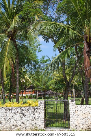 Door to paradise (tropical garden with a luxury villa at background)