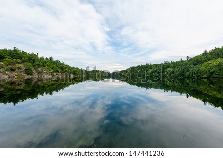 The canadian lake in the forest under the cloudy sky