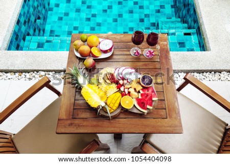 Tropical fruit plate by the hotel pool for two, top view from above. Summer healthy diet, vegan breakfast. Tasty vacation concept.