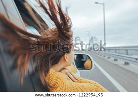 Rear view of pre teen girl in car looking forward on a bridge at weekend road trip