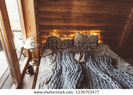 Rustic interior decoration of log cabin bedroom. Cozy warm blanket on bed by window.