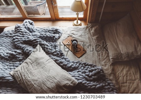 Rustic interior decoration of log cabin bedroom. Cozy warm blanket on bed by window, top view from above.