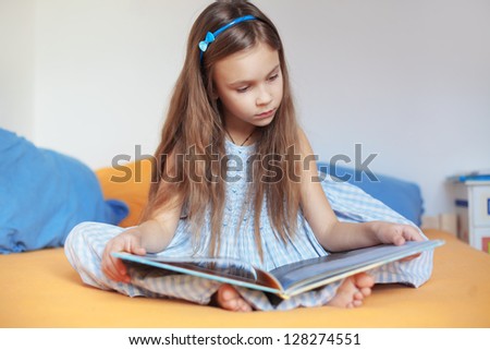 Portrait of 6 years old child reading book at home