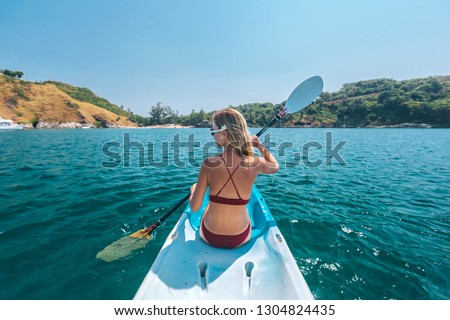 Woman paddling a kayak by the tropical beach. Kayaking tour in Phuket, Thailand